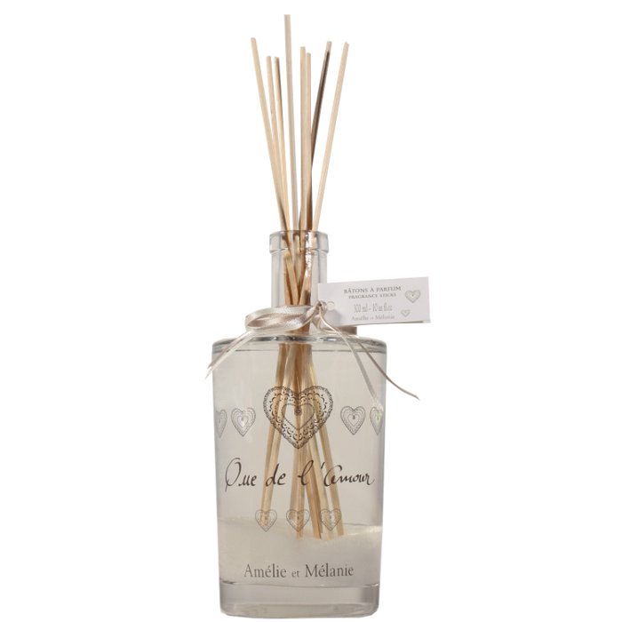 Clear diffuser bottle with wooden sticks and decorative hearts on a white background