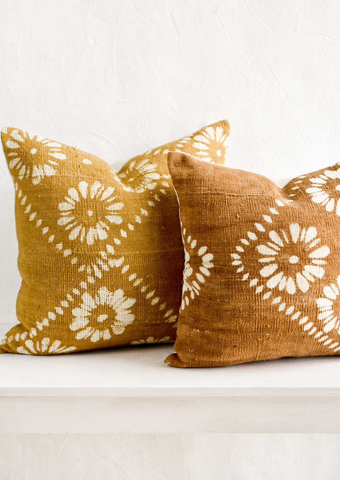 Mustard and brown mudcloth pillows with white floral motif.