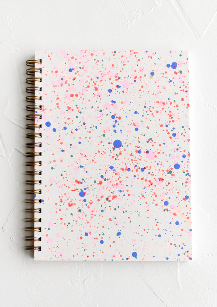 Spiral bound notepad with neon paint splatter cover.