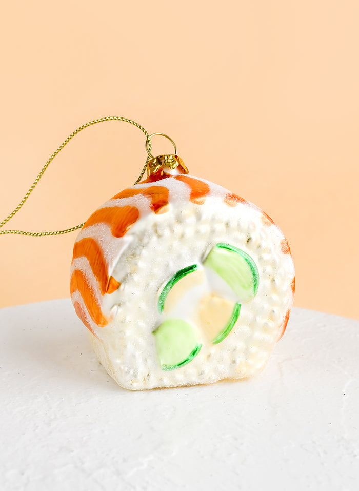 A decorative glass ornament in the shape of salmon avocado sushi roll.