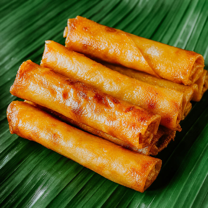 Rolled spring rolls on a green leaf background