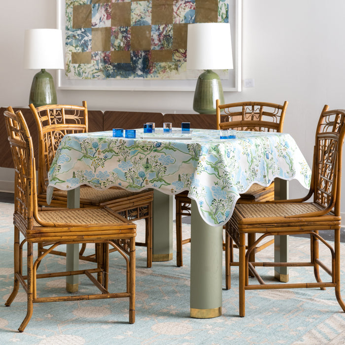 Clear acrylic tic tac toe set with blue and white playing pieces on floral tablecloth-covered round table.