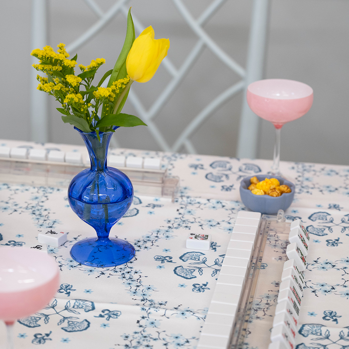 Cobalt blue glass bud vase with a bulbous base holding a yellow tulip and small yellow flowers.