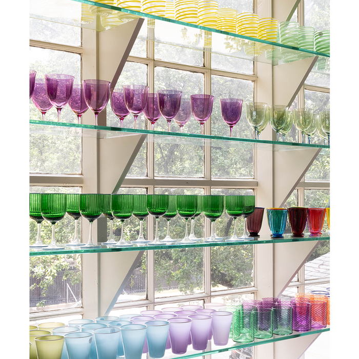 Glass shelves filled with colorful glassware in different shapes and sizes.