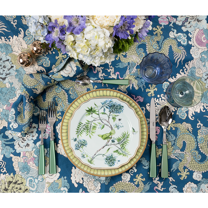 Blue and cream patterned Magic Mountain Napkin with intricate floral and dragon designs under a white plate with bird.