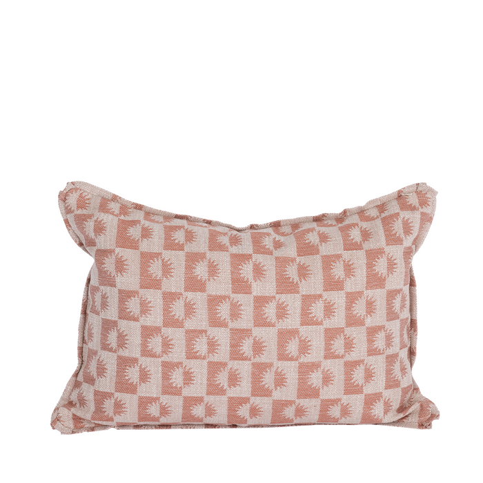 A rectangular lumbar pillow with a pink and white geometric sunburst pattern.