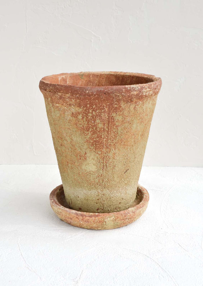 A rustic, heavily textured terracotta clay planter with saucer.
