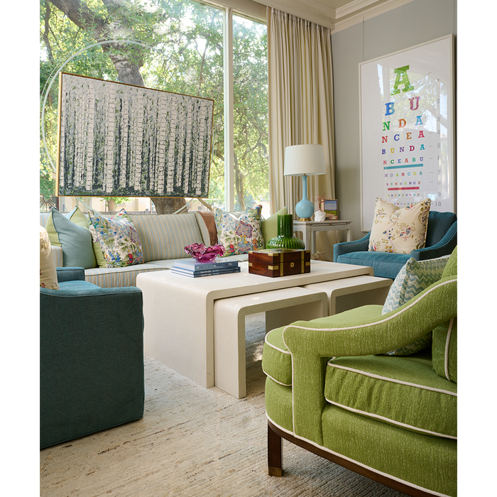 Rectangular lumbar pillow with blue zigzag pattern on white, placed on neutral-toned sofa in bright living room.